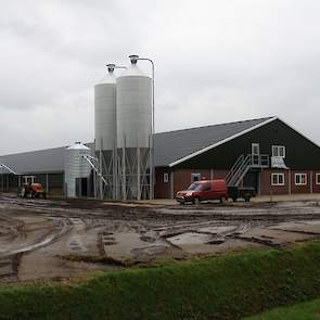 Een overzicht van de voor- en zijkant van de nieuwe stal met vooraan de twee metalen silo’s met de speciale onderbak waarmee ontmenging van het voer voorkomen moet worden.