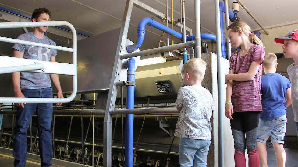 In de melkstal waar hij 110 koeien melkt, legt de melkveehouder uit hoe de koeien lopen en staan wanneer ze melk geven.