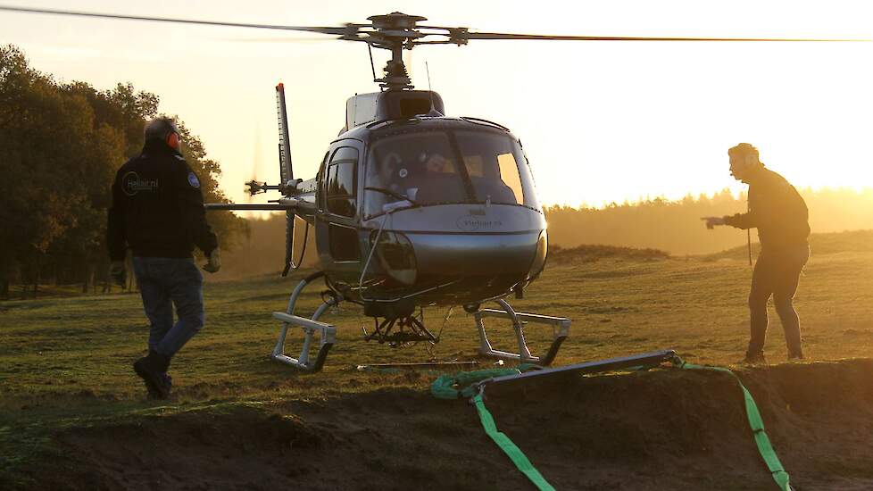 De kuip met schelpengruis wordt aan de helikopter gekoppeld voor het uitstrooien.