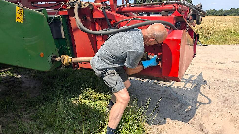 Gerrit Joling is net bij het tweede perceel aangekomen en koppelt de aftakas van de maaibek aan.